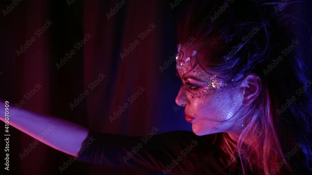 exotic dancer woman is performing lap dance in dark room, closeup of playful flirting face with bright makeup