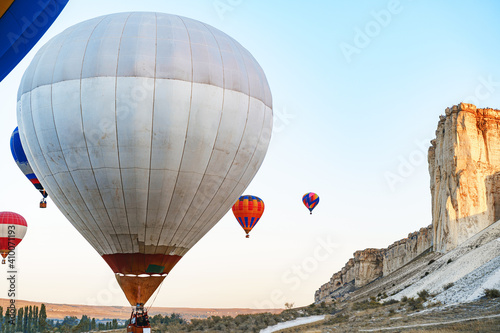 Colorful air balloons flying in clear sky near huge white mountain