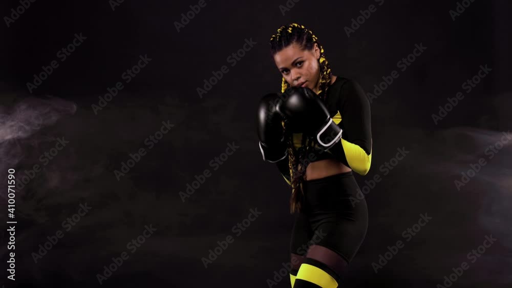 Boxing sport concept. Woman with yellow braids on black background. Girl sportsman muay thai boxer fighting in gloves in gym. Boxing sport concept. Woman with yellow braids on black background. Girl sportsman muay thai boxer fighting in gloves in gym.