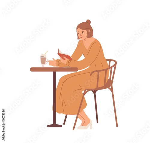 Young woman sitting at table in cafe, reading book and drinking coffee. Color...