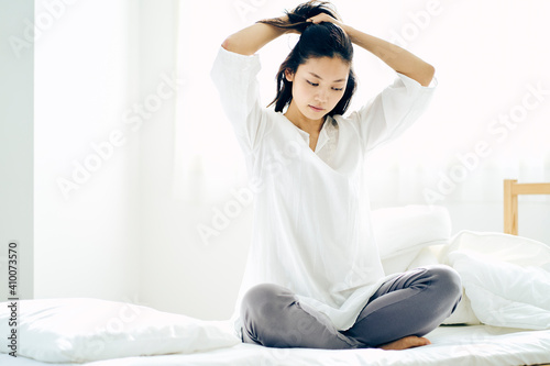 ベッドの上で髪を結う30代日本人女性