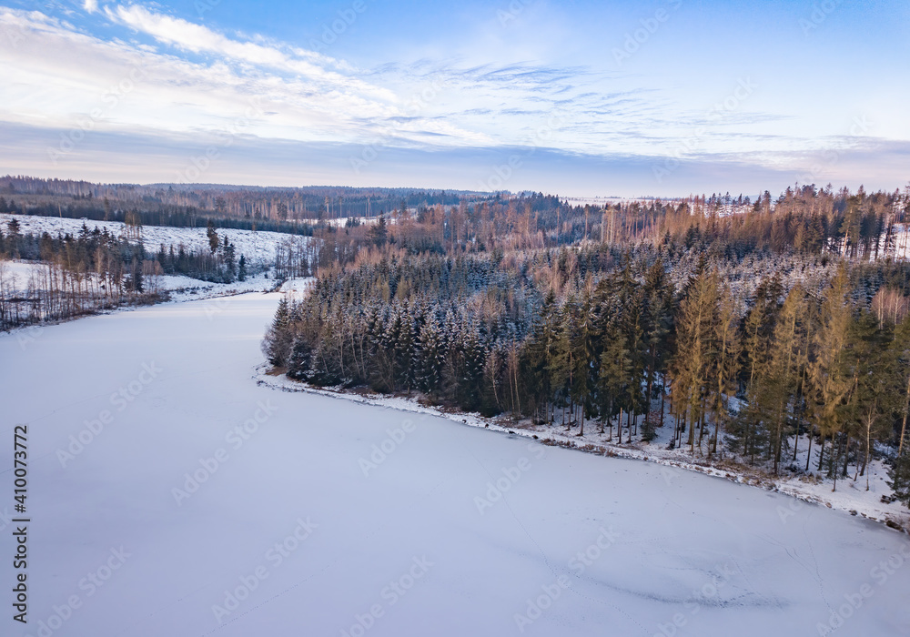 Aerial bird view of beautiful winter landscape with frozen water reservoir situated in forest covered with snow. European countryside. Czech Republic, Vysocina Highland region, Europe