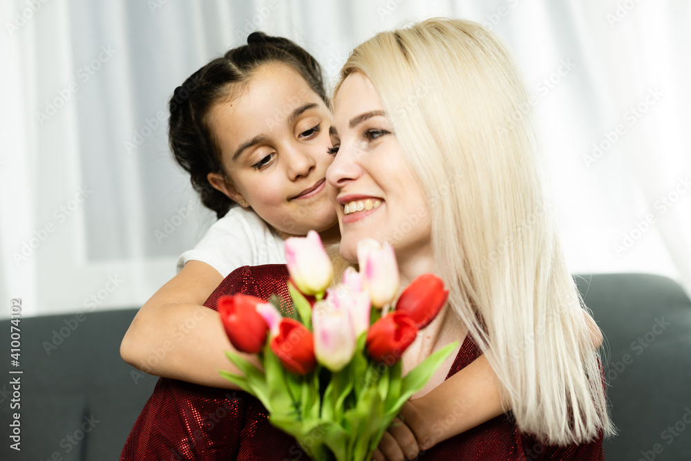 Woman and child with bouquet of flowers against home background. Spring family holiday concept. Women's day Woman and child with bouquet of flowers against home background. Spring family holiday concept. Women's day