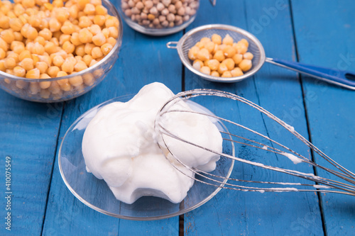 Close-up of a white whipped chickpea Aquafaba on a blue background. Aquafaba is a great substitute for chicken eggs with vegetable protein from chickpeas. It is used in recipes for vegans.