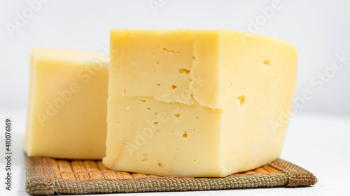 A cut piece of hard cheese close-up on a light background.
