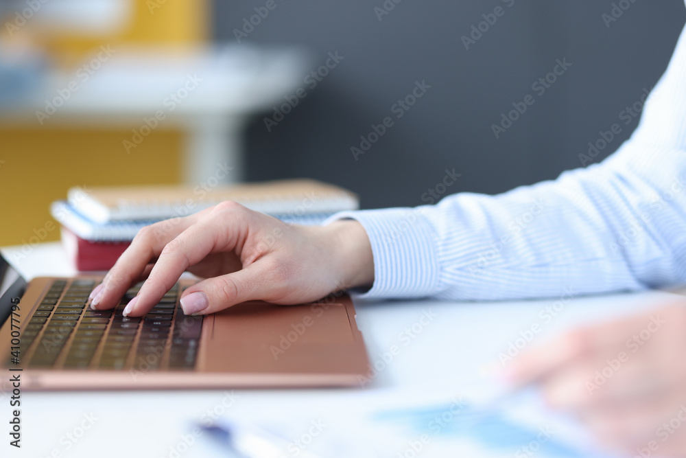 Female hands typing on laptop keyboard at workplace