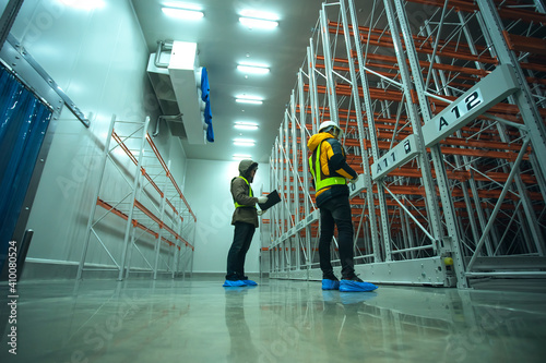 Slika na platnu Two technician inspector check machine shelf in cold warehouse.