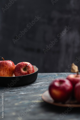 Fresh red apples on a plate on a wooden background. Red apples on a dark background. Selective focus