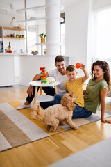 Happy family playing, having fun with dog at home