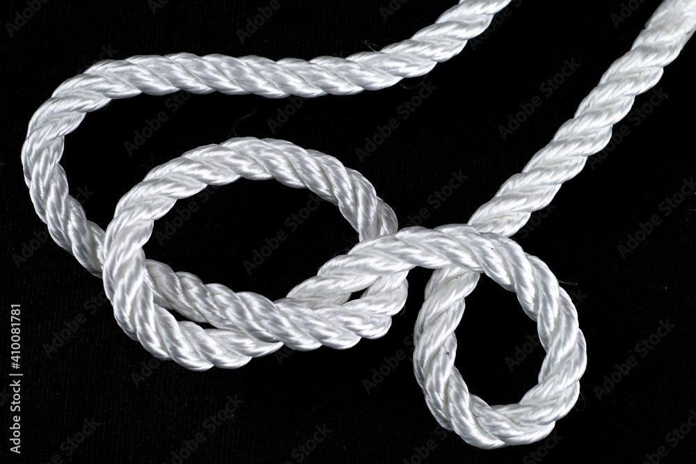 piece of white rope tied in a knot on black background piece of white rope tied in a knot on black background
