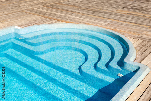 Foto New modern fiberglass plastic swimming pool entrance step with clean fresh refreshing blue water on bright hot summer day at yard or resort hotel spa area