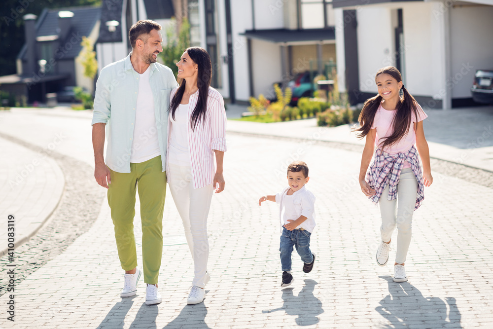 Fototapeta premium Full length body size view of four cheerful people dad mom small little kids embracing going outside enjoying leisure good weather