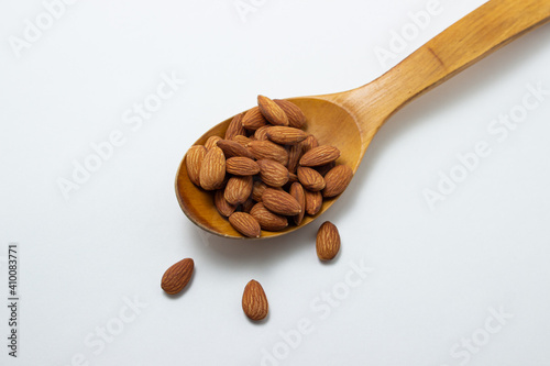 Almonds on a white background. Isolated almonds. Roasted almonds in a wooden spoon