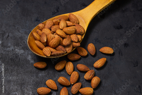 Almonds on a black background. Isolated almonds. Roasted almonds in a wooden spoon