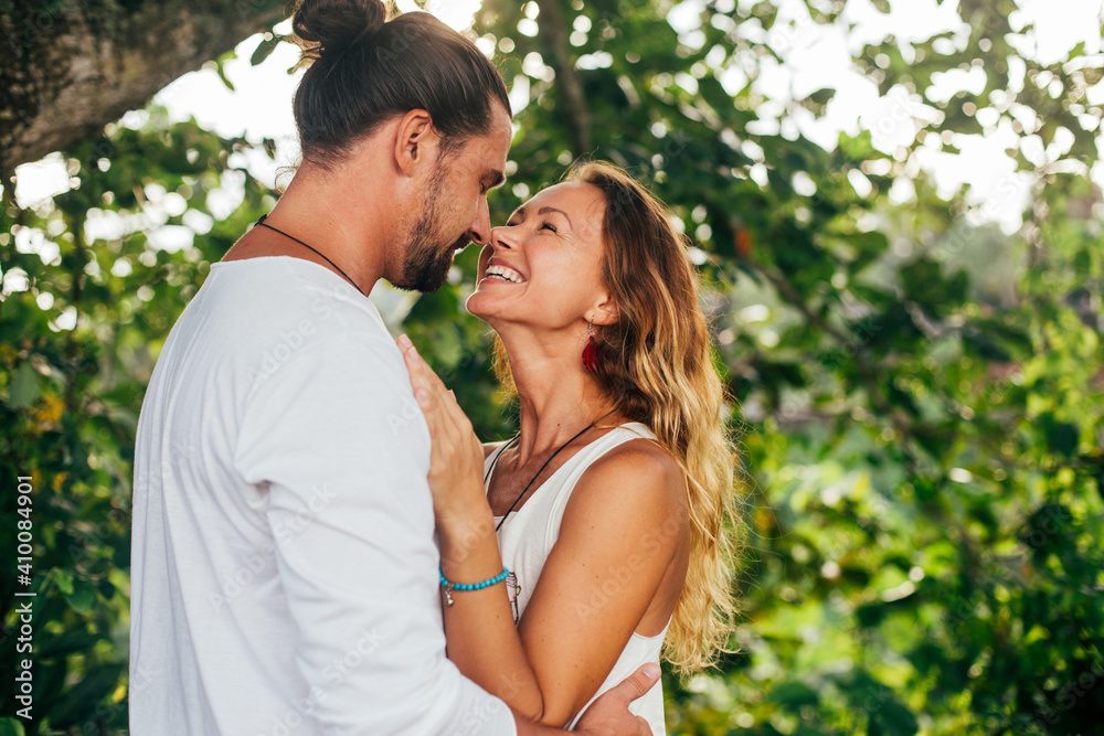 long haired man hugs his delicate curly woman in the lights of sunset long haired man hugs his delicate curly woman in the lights of sunset