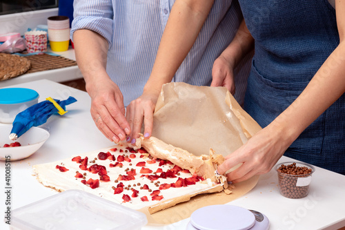 The process of making a meringue roll with strawberries with women's hands. Selective focus.