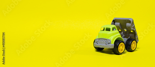 Toy truck car on a yellow background - construction equipment for children. Bright children s plastic toys  dump truck childhood.