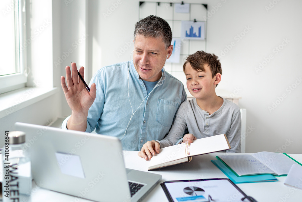 Fototapeta premium Father working from home having a video call while son doing homework.