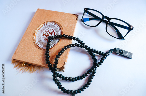 Islamic Holy book Quran/ Koran with prayer beads rosary and eyeglasses over white background