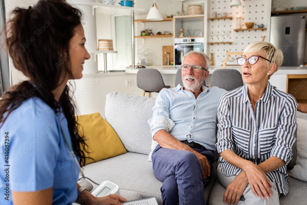 Obraz premium Female nurse talking to seniors patients while being in a home visit, senior couple signs an insurance policy.