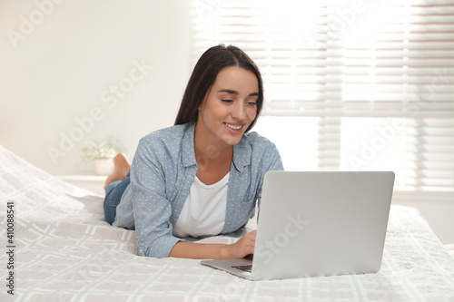 Woman using laptop for search on bed at home © New Africa