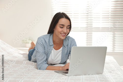 Woman using laptop for search on bed at home