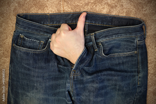 Obraz na plátně A man's hand, with his thumb raised, protrudes from the fly of his jeans