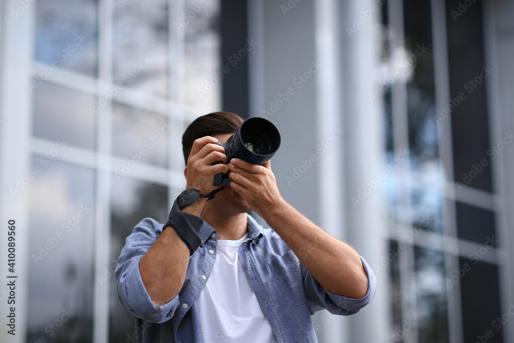 Photographer taking picture with professional camera on city street