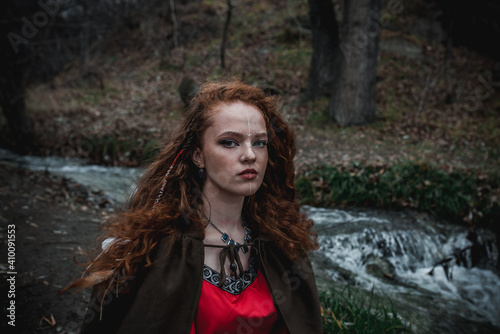 Foto Red-haired woman in a red dress in a historical Celtic costume in the autumn for