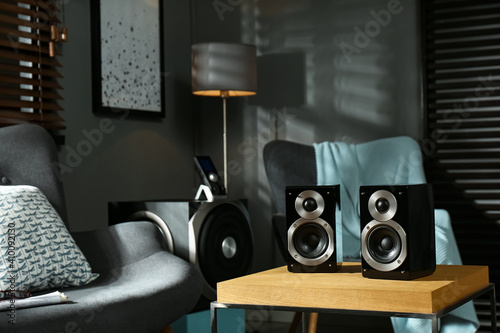 Modern audio speaker system on wooden table in living room photo