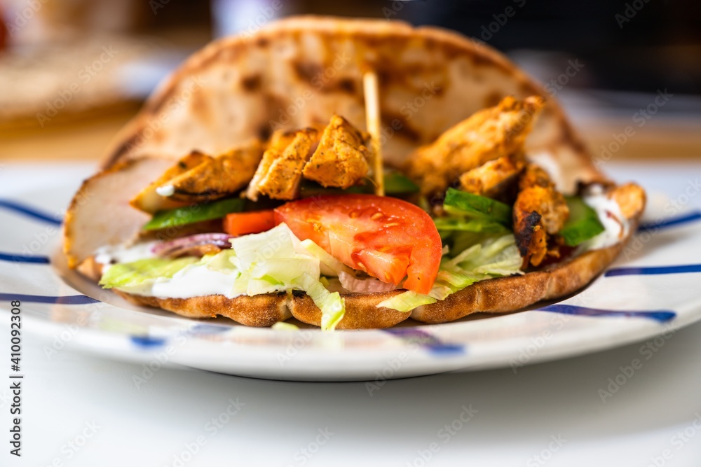 Chicken pieces in pita bread with vegetable salad( shawarma) on plate.