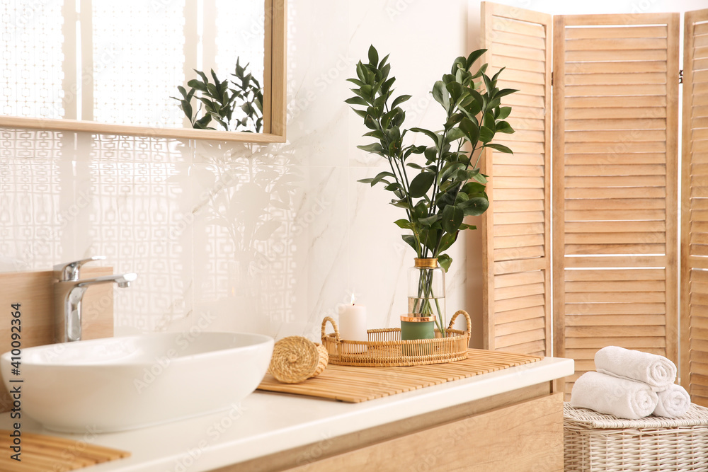 Fototapeta premium Vase with beautiful branches and fresh towels near vessel sink in bathroom. Interior design