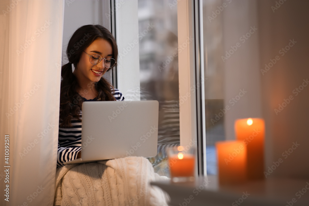 Young woman using laptop near window at home. Winter atmosphere - obrazy, fototapety, plakaty 