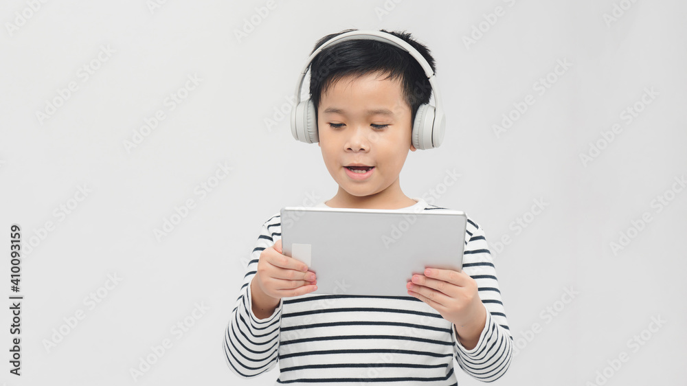 technology - a lovely young pupil standing with his tablet wearing headphones technology - a lovely young pupil standing with his tablet wearing headphones