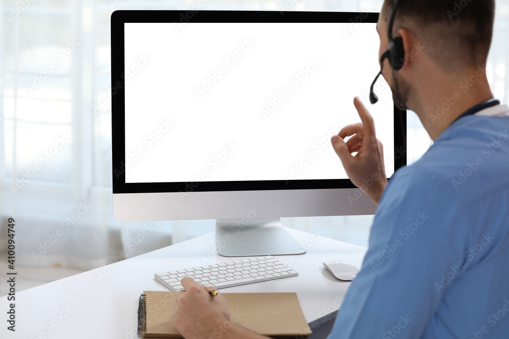 Doctor with headset consulting patient online at desk in clinic, space for text. Health service hotline Doctor with headset consulting patient online at desk in clinic, space for text. Health service hotline