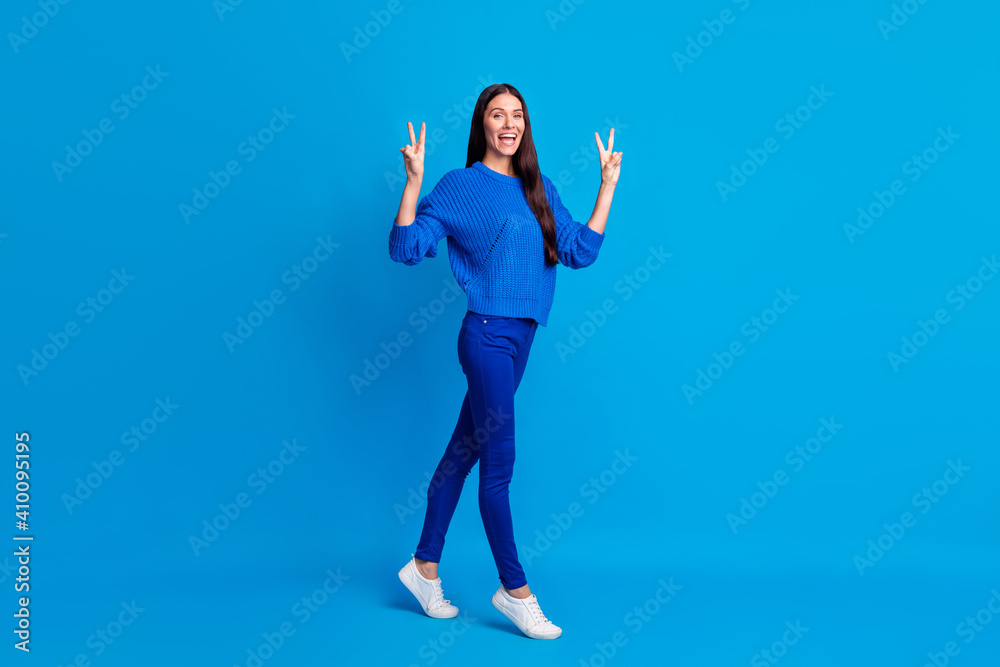 Full length profile side photo of cheerful happy young lady make two v-signs go isolated on blue color background Full length profile side photo of cheerful happy young lady make two v-signs go isolated on blue color background