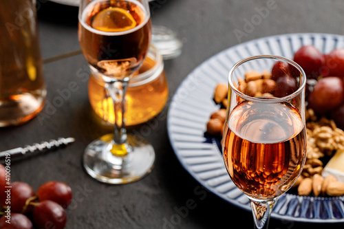 Glass of wine and plate with nuts on black table