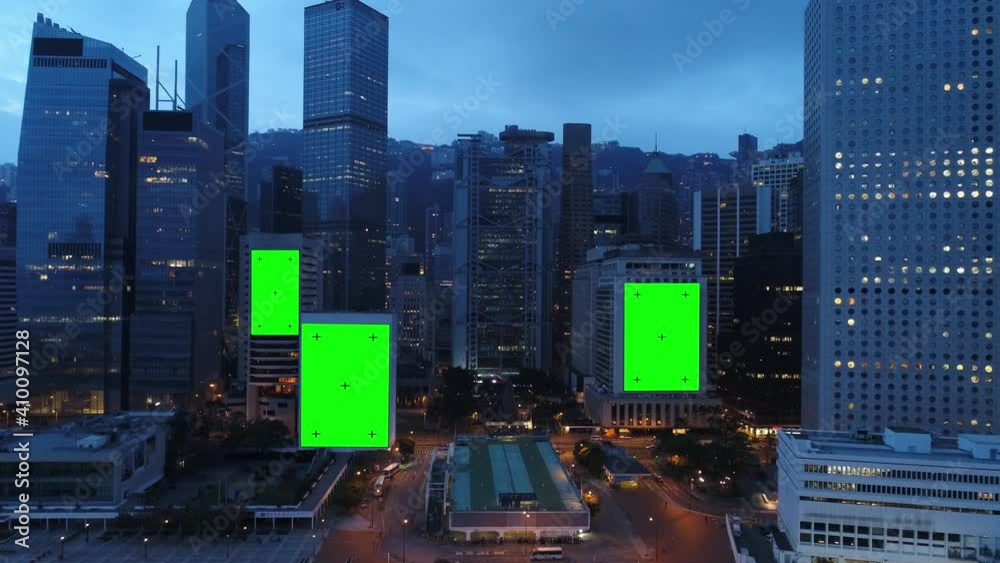 AERIAL. Top view of skyscrapers and green screen build board with tracking point. Bird view of modern city at night streets.