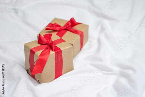Red gift kraft box with ribbon. Valentine's Day gift in bed. Natural eco and bio gift. Sensual passion minimal gift in bed