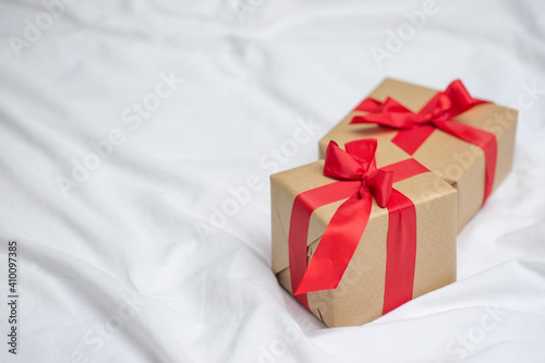 Red gift kraft box with ribbon. Valentine's Day gift in bed. Natural eco and bio gift. Sensual passion minimal gift in bed © Ruth