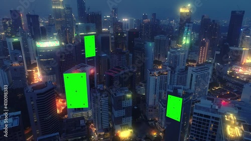 AERIAL. Top view of skyscrapers and green screen build board with tracking point. Bird view of modern city at night streets.