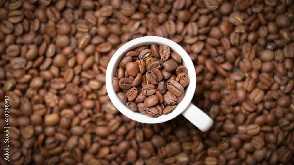 cup of coffee full of roasted coffee beans (rotating) cup of coffee full of roasted coffee beans (rotating)