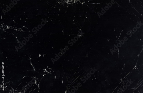 Cracked texture background. Damaged screen. Black smashed dirty surface with dust scratches smeared stains grain noise abstract pattern copy space wallpaper.