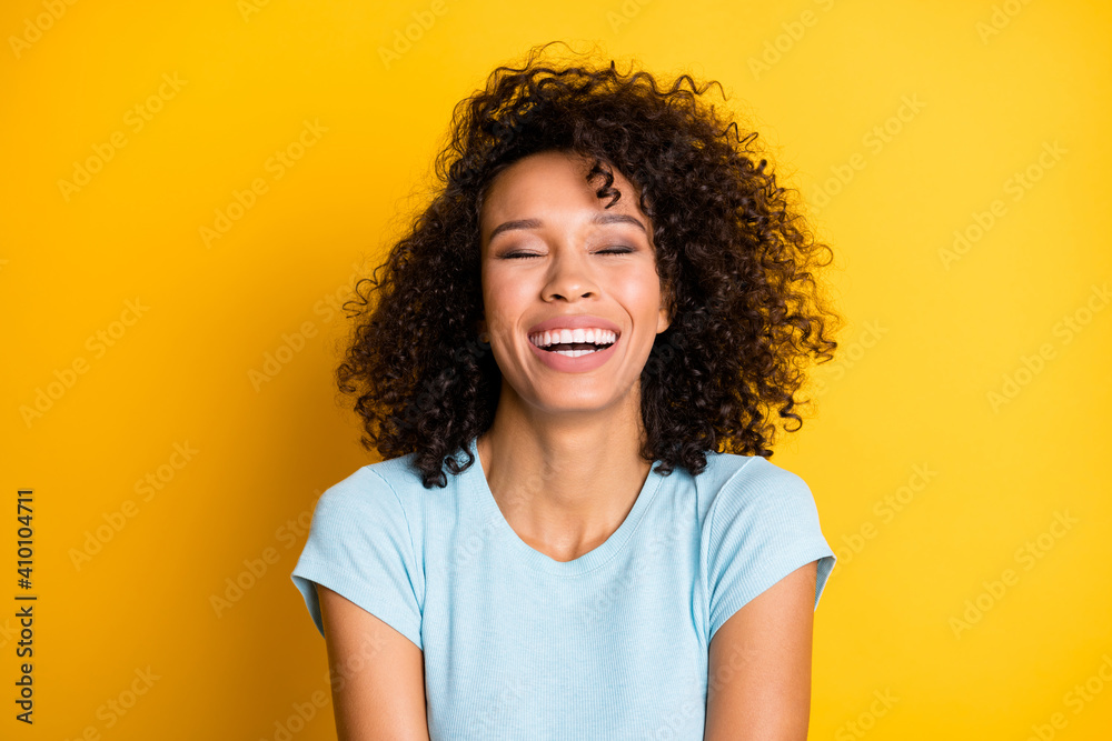 Photo of adorable funny dark skin curly woman dressed blue t-shirt laughing closed eyes isolated yellow color background Photo of adorable funny dark skin curly woman dressed blue t-shirt laughing closed eyes isolated yellow color background