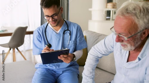 Male nurse talking to senior man while being in a home visit. photo