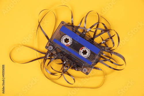 Foto Old cassette tape with unwound tape on a yellow background.