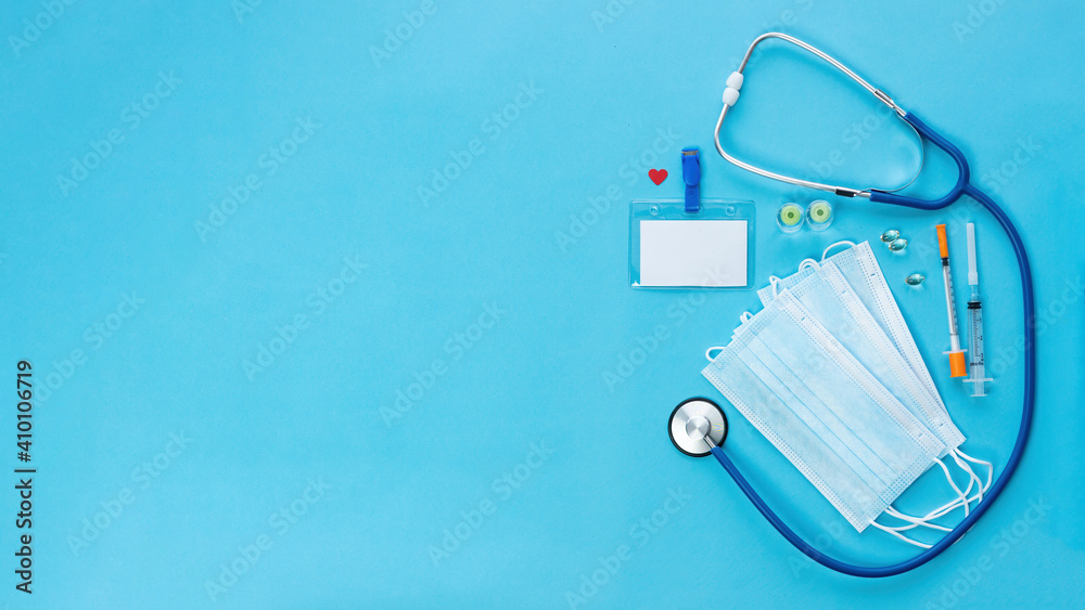 Promotional banner with medical items and blank doctor badge on blue background with copy space. COVID-19 coronavirus vaccination concept banner. Health and life insurance concept. Promotional banner with medical items and blank doctor badge on blue background with copy space. COVID-19 coronavirus vaccination concept banner. Health and life insurance concept.