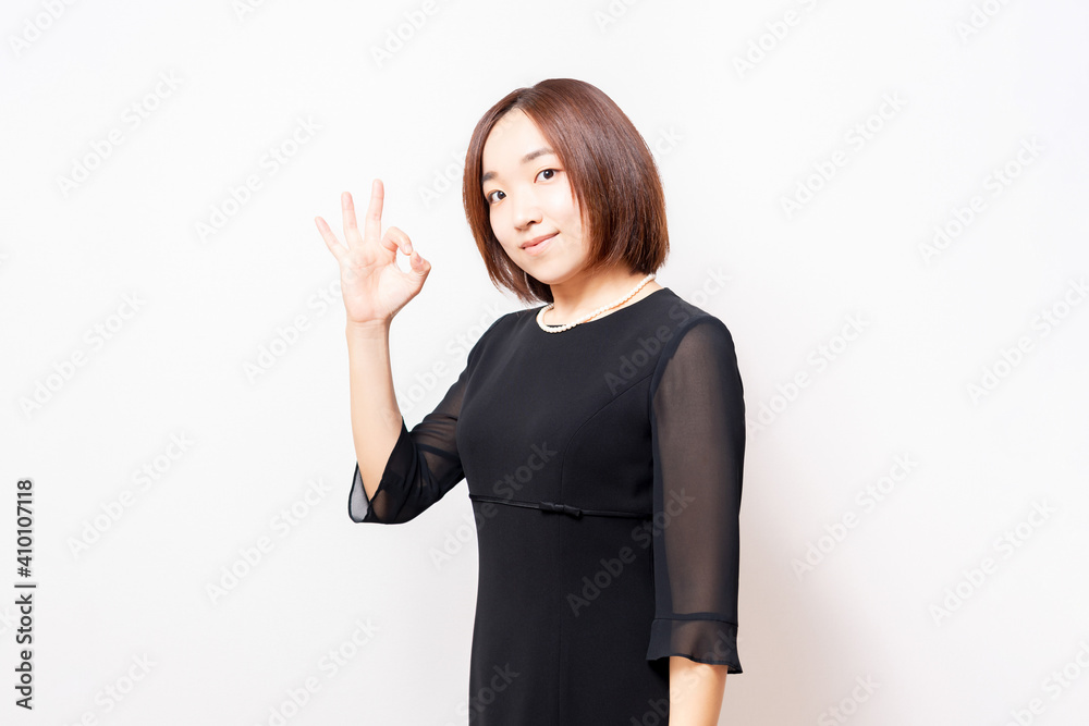 白背景の前に立って、OKのジェスチャーをする喪服を着た女性 白背景の前に立って、OKのジェスチャーをする喪服を着た女性