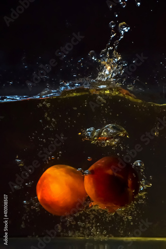Two peaches thrown into water, together with air bubbles and light refraction