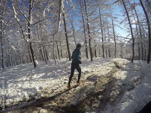 Young guy running in a sunny winter day, in snowy mountains